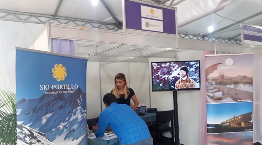 Feira de turismo com stands promocionais, banners e equipe atendendo visitantes em evento de viagens e lazer.